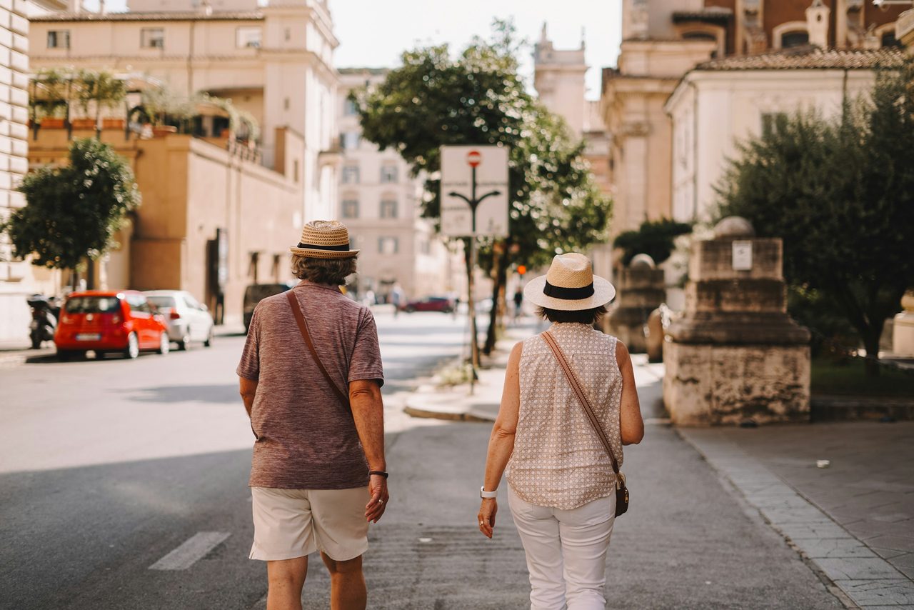 Paar mit Sonnenhüten spaziert durch eine italienische Altstadt